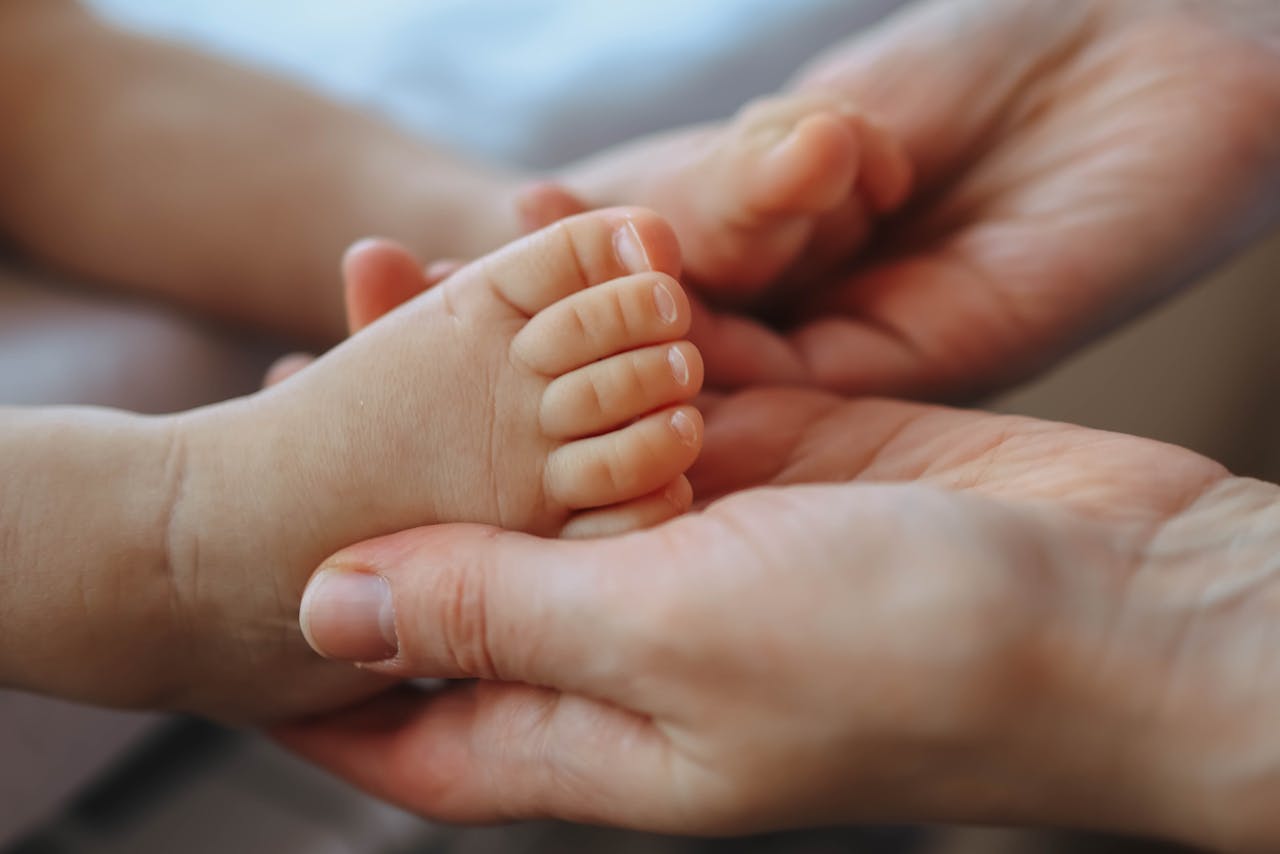 The Art of Drawing Readers In: Your attractive post title goes here Close-up of a parent's hands gently cradling a newborn's foot, symbolizing care and tenderness.